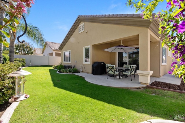 rear view of property featuring a lawn and a patio area