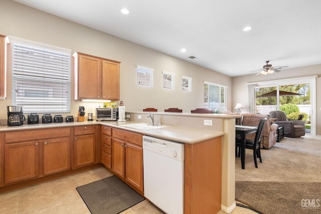 kitchen featuring kitchen peninsula, white dishwasher, light colored carpet, ceiling fan, and sink