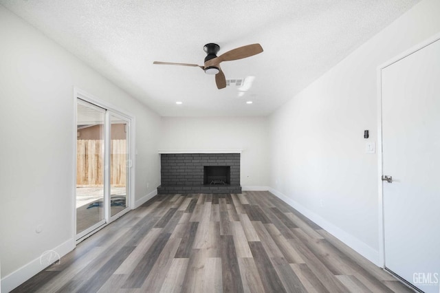 unfurnished living room featuring wood finished floors, ceiling fan, a fireplace, and visible vents