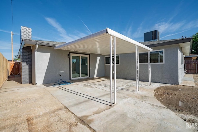 rear view of house with a patio, central air condition unit, stucco siding, a chimney, and fence