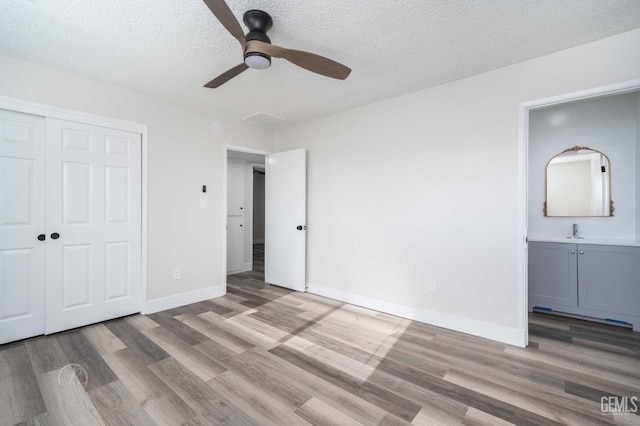 unfurnished bedroom with baseboards, a closet, a textured ceiling, and wood finished floors