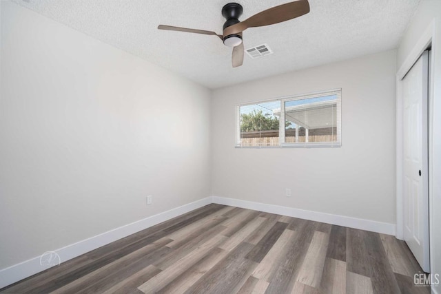 unfurnished bedroom featuring visible vents, a closet, a ceiling fan, a textured ceiling, and wood finished floors