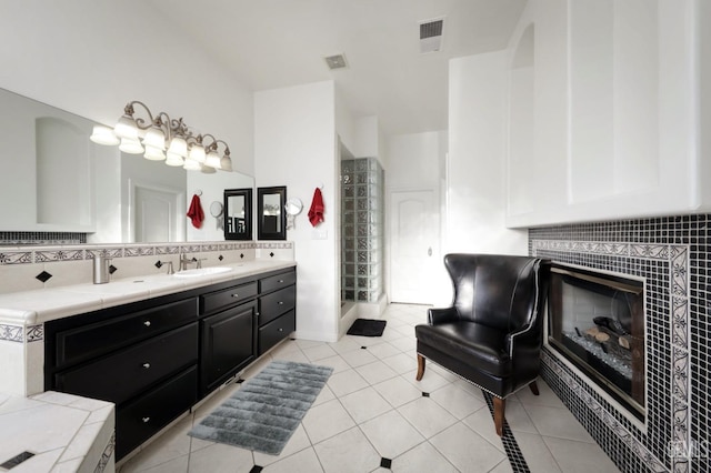 bathroom featuring tile patterned flooring, decorative backsplash, a tiled fireplace, and vanity