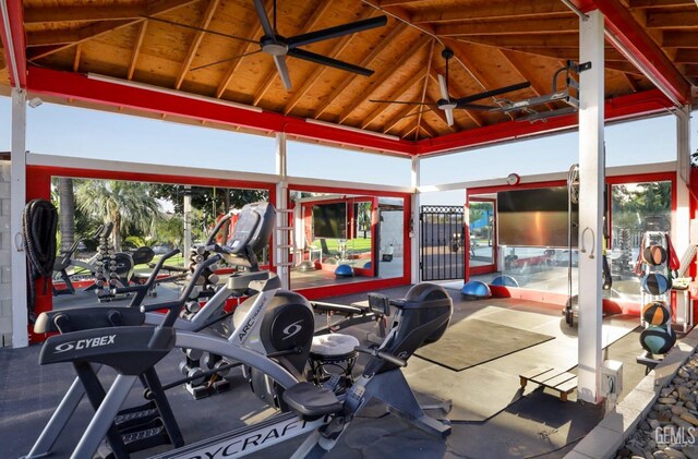 exercise room with ceiling fan and high vaulted ceiling