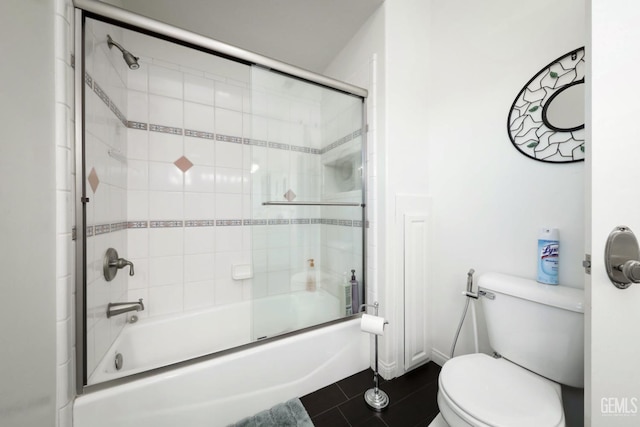 bathroom with toilet, tile patterned floors, and combined bath / shower with glass door