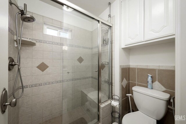 bathroom with toilet, tile walls, and walk in shower