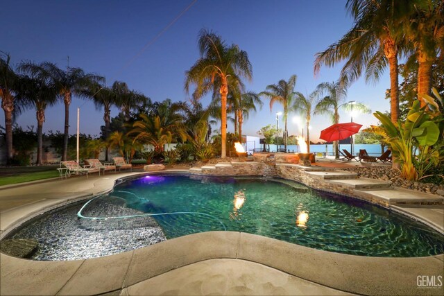 pool at dusk with a patio area