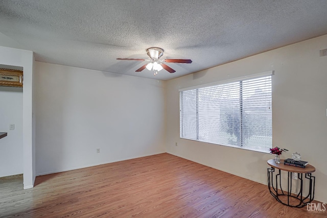 spare room featuring a textured ceiling, light hardwood / wood-style flooring, and ceiling fan