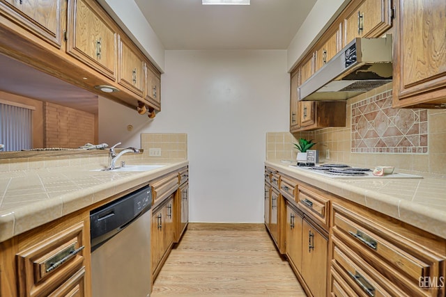 kitchen featuring tile countertops, dishwasher, premium range hood, sink, and light hardwood / wood-style floors