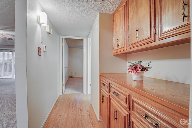 corridor with light hardwood / wood-style flooring and a textured ceiling