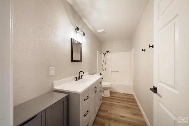 full bath featuring baseboards, shower / washtub combination, toilet, wood finished floors, and vanity