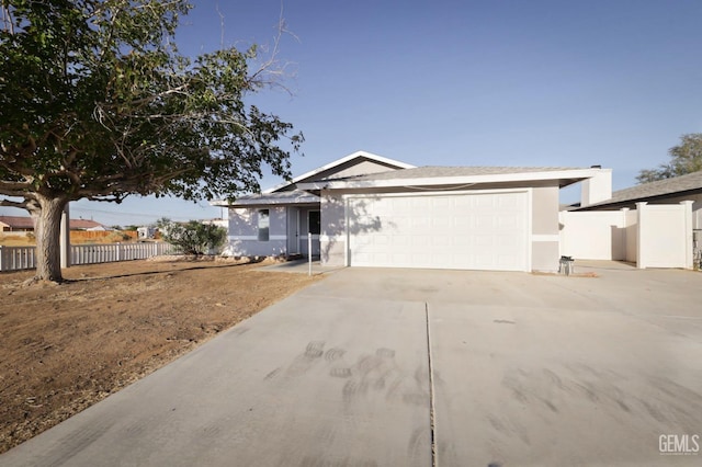 single story home featuring stucco siding, an attached garage, concrete driveway, and fence