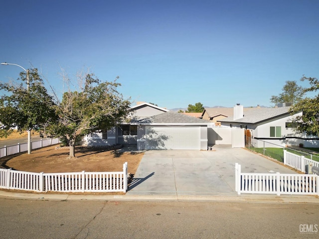 view of front of property with concrete driveway and a fenced front yard