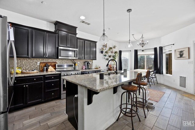 2004 Suncrisp Ln, Bakersfield, CA 93312 - kitchen featuring appliances with stainless steel finishes, dark cabinetry, tasteful backsplash, a kitchen bar, and recessed lighting