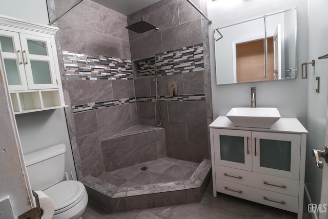 full bath with toilet, a tile shower, and vanity