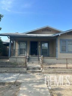 bungalow-style home with covered porch and fence