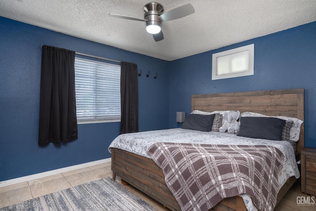 tiled bedroom with baseboards, a textured ceiling, and ceiling fan