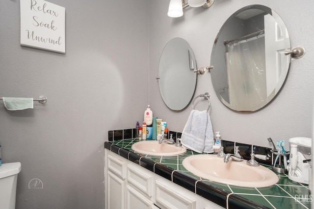 full bath featuring curtained shower, double vanity, toilet, and a sink