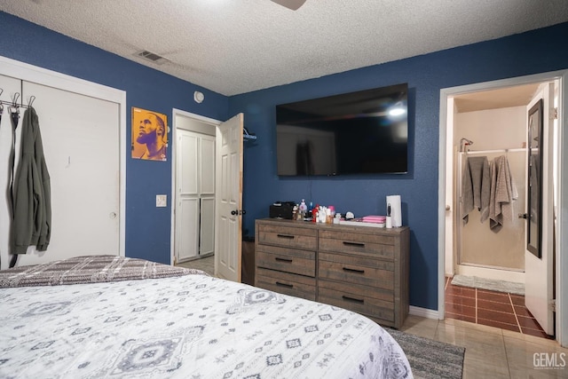 bedroom with tile patterned floors, visible vents, a textured ceiling, a closet, and connected bathroom