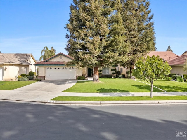 view of front of property with a garage, concrete driveway, a tile roof, a front lawn, and stucco siding