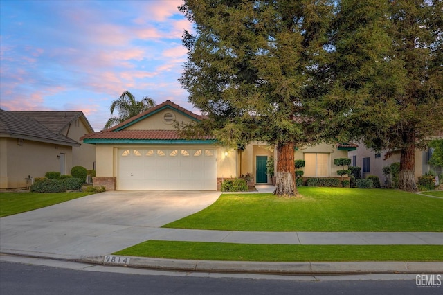 view of front facade with concrete driveway, a lawn, an attached garage, and stucco siding