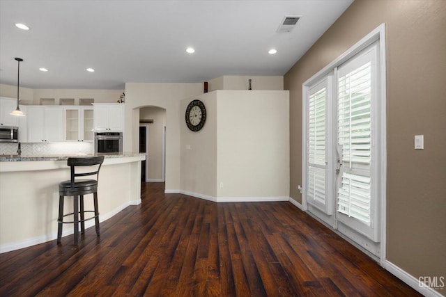 9508 Canyon Lake Ct, Bakersfield, CA 93312 - unfurnished living room featuring arched walkways, recessed lighting, baseboards, dark wood-type flooring, and visible vents