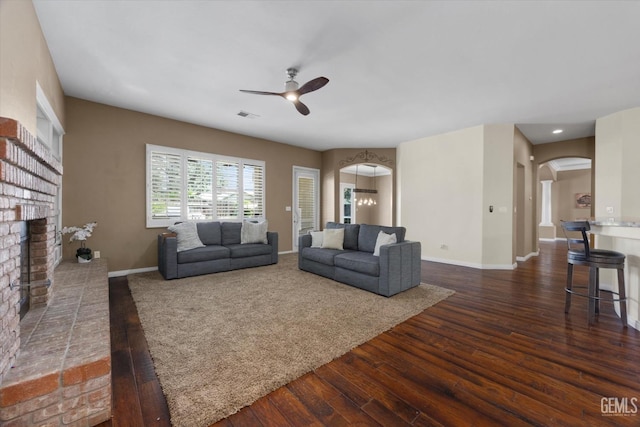9508 Canyon Lake Ct, Bakersfield, CA 93312 - living area with visible vents, a ceiling fan, a brick fireplace, dark wood-type flooring, and arched walkways
