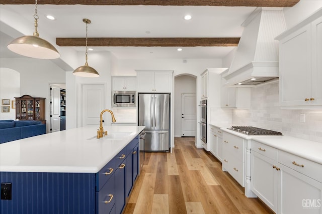 16711 Keystone Pl, Bakersfield, CA 93314 - kitchen with stainless steel appliances, blue cabinetry, arched walkways, custom exhaust hood, and white cabinetry