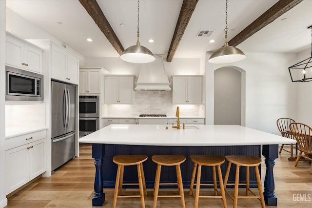 16711 Keystone Pl, Bakersfield, CA 93314 - kitchen with stainless steel appliances, custom exhaust hood, light wood-style floors, decorative backsplash, and beamed ceiling