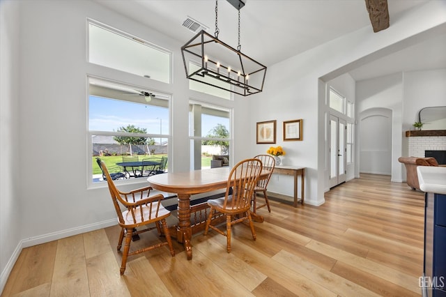 16711 Keystone Pl, Bakersfield, CA 93314 - dining room featuring healthy amount of natural light, light wood-style flooring, a chandelier, and a brick fireplace