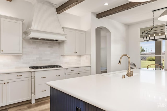 16711 Keystone Pl, Bakersfield, CA 93314 - kitchen with premium range hood, stainless steel gas stovetop, beamed ceiling, arched walkways, and light wood-type flooring
