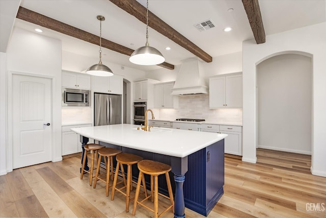 16711 Keystone Pl, Bakersfield, CA 93314 - kitchen featuring stainless steel appliances, arched walkways, premium range hood, a breakfast bar, and decorative backsplash