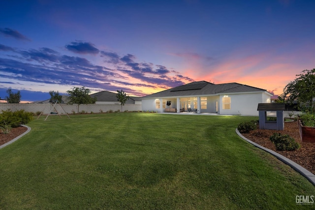 16711 Keystone Pl, Bakersfield, CA 93314 - back of property at dusk featuring roof mounted solar panels, a fenced backyard, and a patio