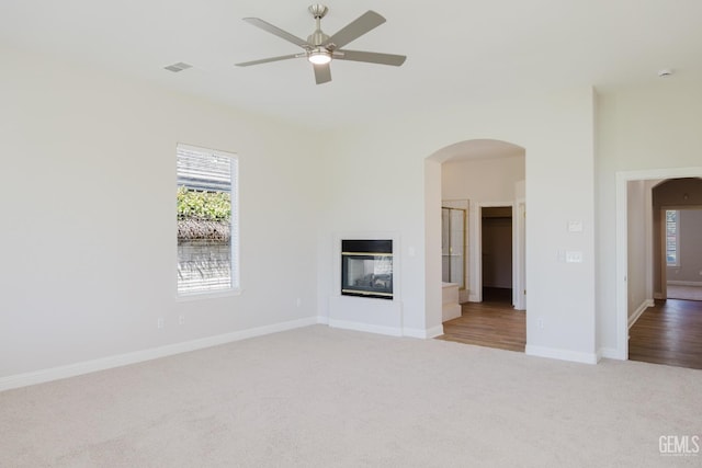 1715 Norwich Way, Bakersfield, CA 93311 - unfurnished living room featuring carpet, arched walkways, a multi sided fireplace, and ceiling fan