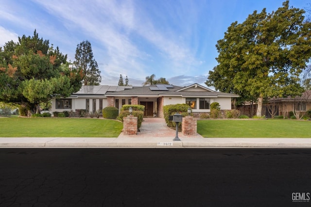 single story home featuring fence, solar panels, and a front yard