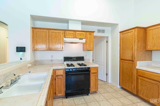 4810 Bluestone Dr, Bakersfield, CA 93311 - kitchen featuring gas range oven, under cabinet range hood, tile counters, and brown cabinetry