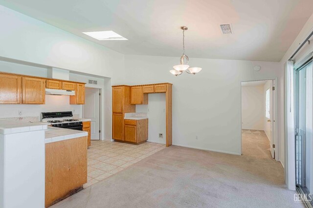 4810 Bluestone Dr, Bakersfield, CA 93311 - kitchen with white gas stove, under cabinet range hood, lofted ceiling, tile countertops, and a chandelier