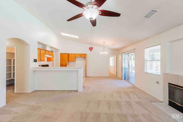 4810 Bluestone Dr, Bakersfield, CA 93311 - unfurnished living room featuring vaulted ceiling, light colored carpet, a tiled fireplace, ceiling fan, and arched walkways