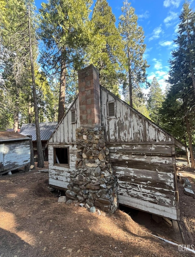 view of side of home with metal roof and a chimney