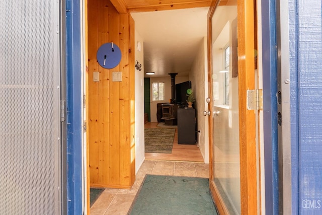 corridor with a healthy amount of sunlight, light tile patterned floors, and wooden walls