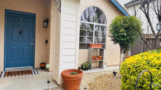 property entrance featuring stucco siding and fence