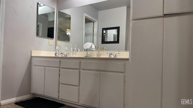bathroom featuring baseboards and double vanity