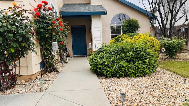 entrance to property featuring fence and stucco siding