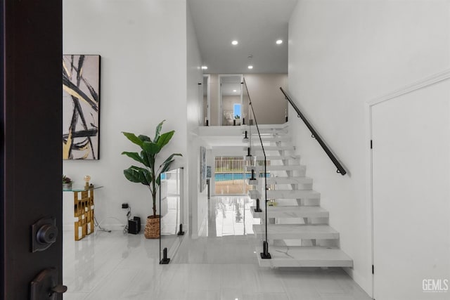 entryway featuring recessed lighting, stairs, and a towering ceiling