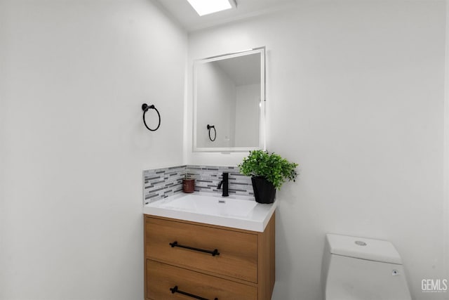 half bath featuring tasteful backsplash, toilet, and vanity
