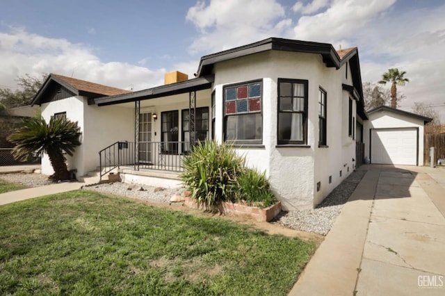 view of front of house with stucco siding, a front yard, an outbuilding, and driveway