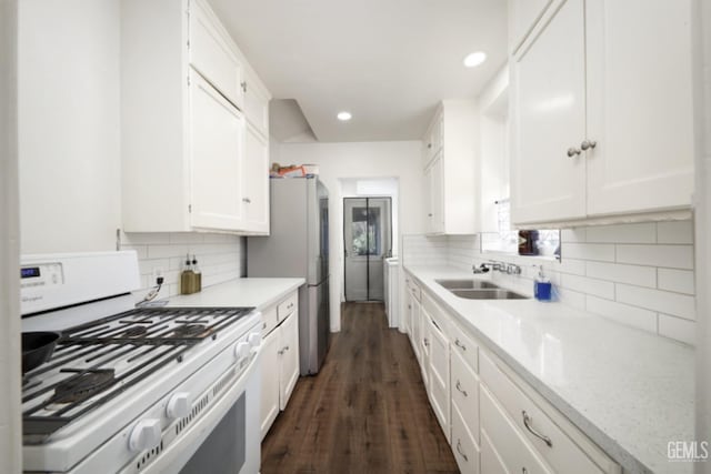 kitchen with a sink, backsplash, white gas stove, and white cabinets