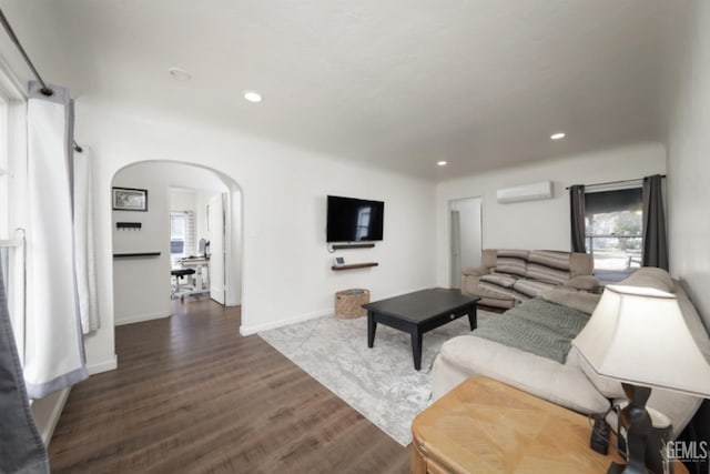 living area with recessed lighting, arched walkways, wood finished floors, and a wall unit AC