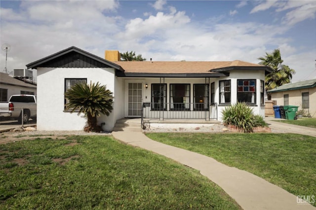 view of front of property with stucco siding, a porch, and a front lawn