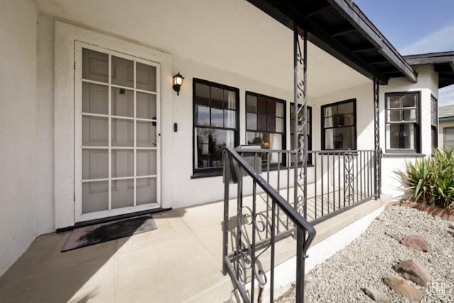 property entrance featuring stucco siding and covered porch